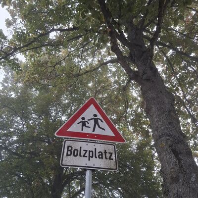 Das Bild zeigt ein dreieckiges Verkehrszeichen mit spielenden Kindern und rotem Rand. Darunter ist der Schriftzug Bolzplatz zu lesen. - Zum Artikel: Zwei Bolzpl&auml;tze gesperrt